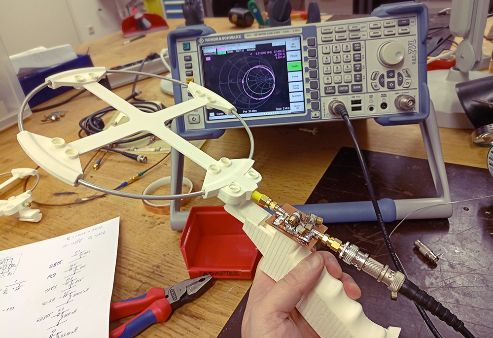 Один из первых прототипов антенны с платкой согласования. На заднем плане - векторный анализатор, показывающий диаграмму Смита.