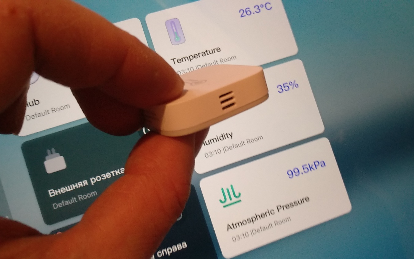 Поскольку датчик измеряет три параметра — он добавляет в интерфейс три «карточки» с данными. На этом фото — на заднем плане уже добавленные карточки, а впереди видны прорези в датчике, через которые он анализирует окружающую среду. Пока я его устанавливал в приложение Aqara Home, я держал его, касаясь пальцами этой прорези — и в момент, когда он добавился — влажность была, по его мнению, около 80%. На этом фото она уже снизилась: я держу его уже иначе. Так что чувствительность у датчика высокая и реагирует он очень быстро.